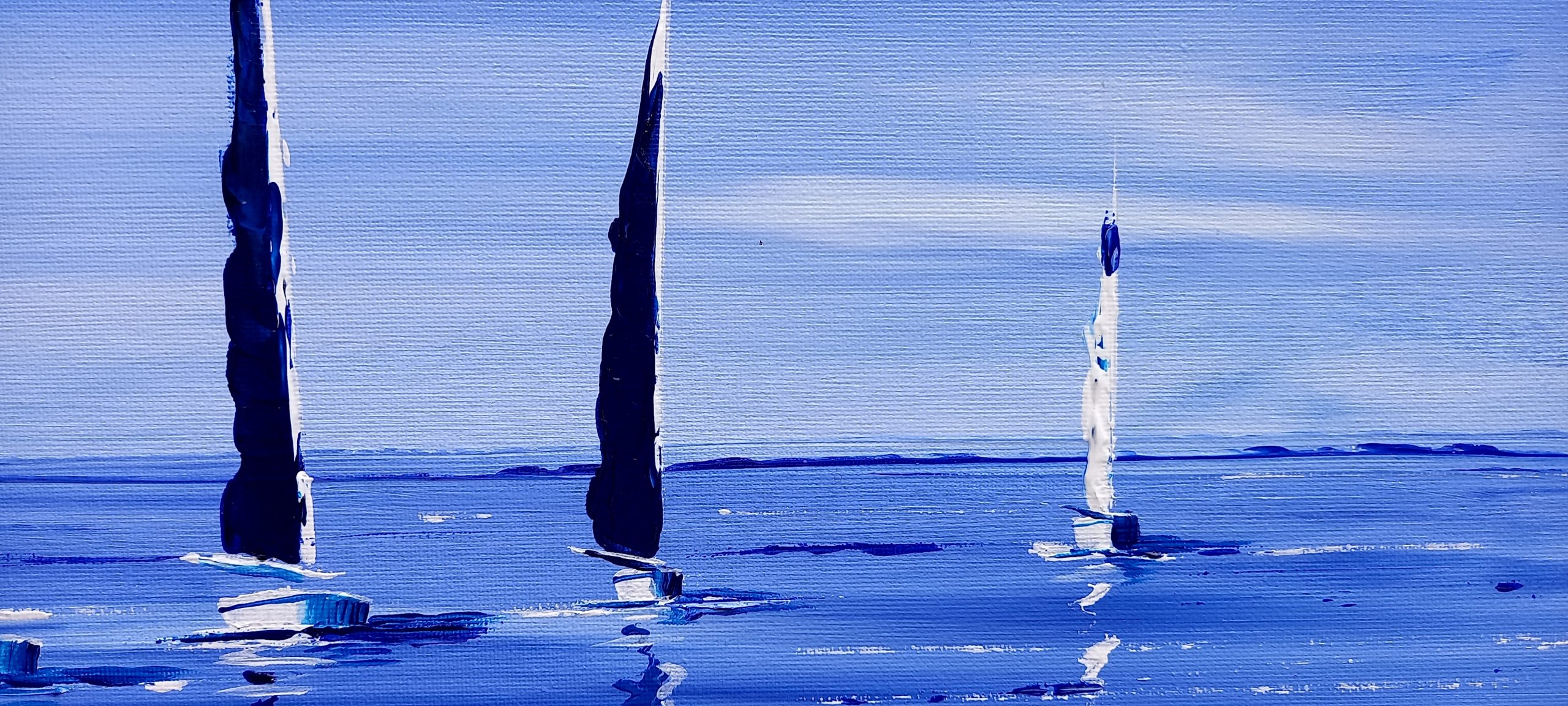 voilier aux voilure bleu marine au loin comme avec comme fond un beau ciel bleu